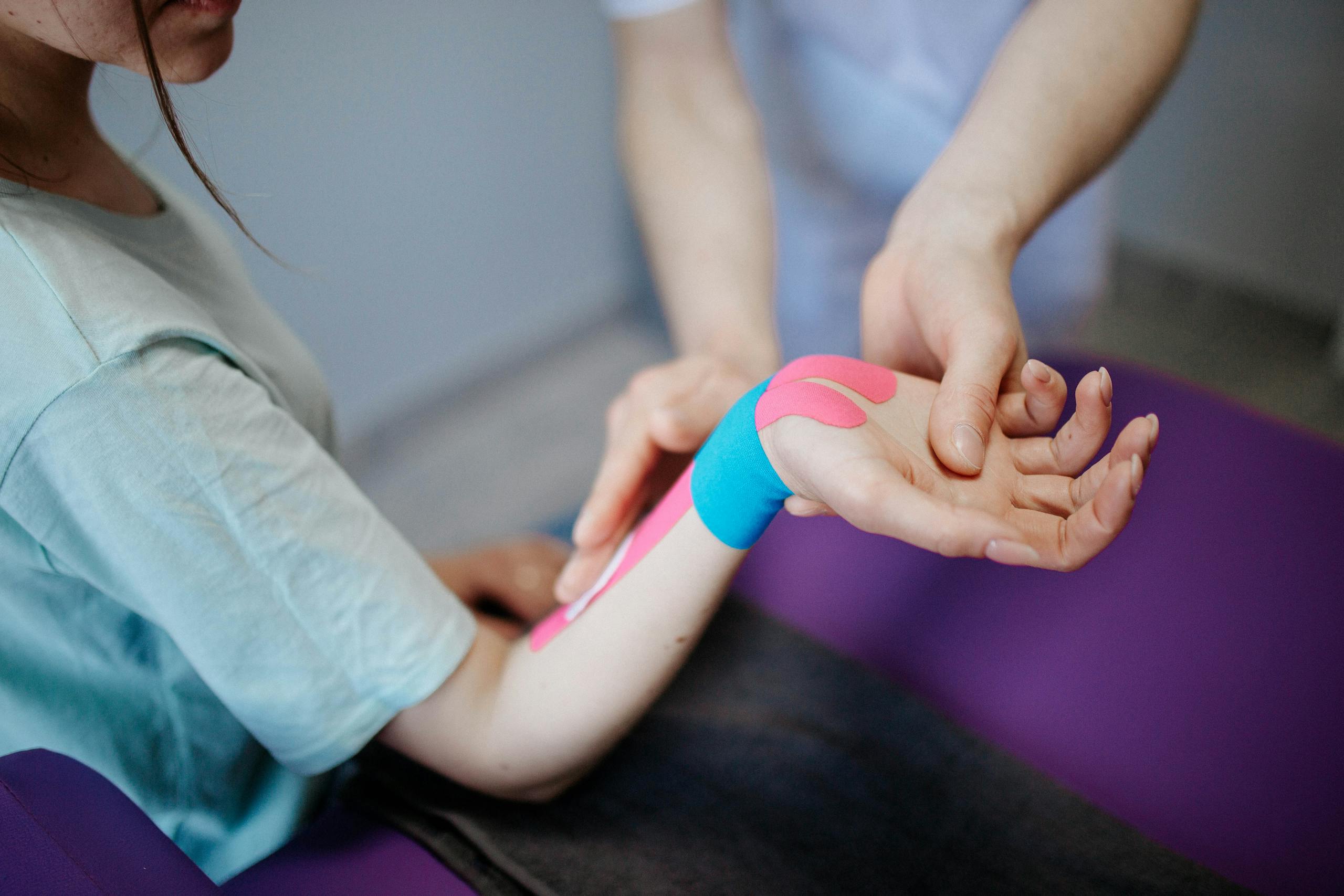 Close-up of a therapist applying kinesio tape for pain relief during a therapy session.