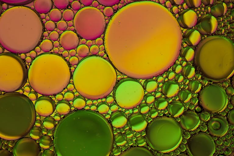 Vibrant abstract pattern of oil and water bubbles in green and yellow hues.